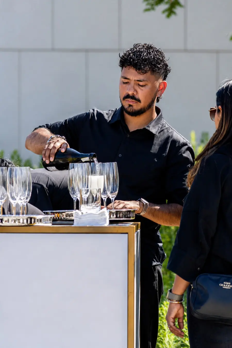 A Cleese server pouring wine at an outdoor bar